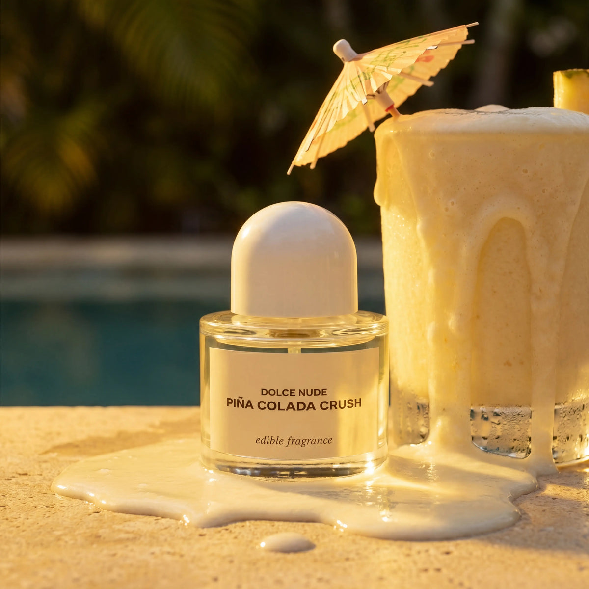 > DOLCE NUDE Piña Colada Crush edible fragrance bottle between sliced pineapples and creamy coconut splashes on tropical backdrop